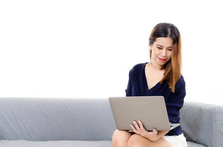 happy beautiful young asian woman using laptop computer on on sofa at home on white background, soft focus, lifestyle smart communication technology, online shopping and payment online conceptの写真素材