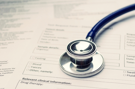 close up stethoscope and patient information form on desk, heart healthcare technology, medical diagnosis, medical report record and history patient concept, selective focus, vintage color toneの写真素材