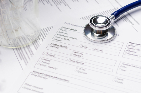 close up stethoscope, test tube, beaker and patient information form on desk, heart healthcare technology, medical diagnosis, medical report record and history patient concept, selective focusの写真素材