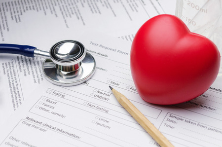 close up stethoscope, pencil, beaker, red heart and patient information form on desk, heart healthcare technology, medical diagnosis, medical report record and history patient concept, selective focusの写真素材