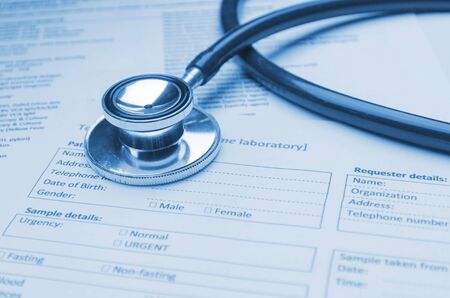 stethoscope and patient information form on desk, heart healthcare technology, medical diagnosis, medical report record, history patient concept, soft and selective focus, blue color toneの写真素材