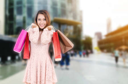 young asian woman beautiful smiling surprise and holding shopping bag while standing at outdoor department store shopping mall, online payment, shopping online, lifestyle conceptの写真素材