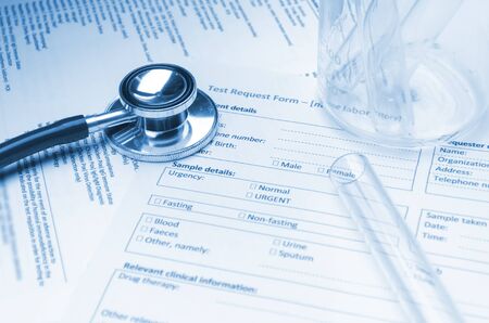 stethoscope, test tube, beaker and patient information form on desk, heart healthcare technology, medical diagnosis, medical report record, history patient concept, soft and selective focus, blue toneの写真素材