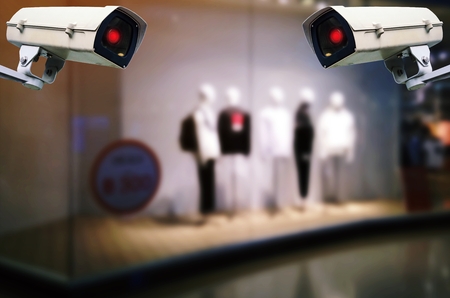CCTV, double security indoor camera system operating with blurred image of showcases fashion clothes...