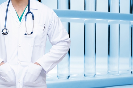 smart doctor with a stethoscope around his neck with bottom view of row of liquid in laboratory test tube background, science, chemical, healthcare technology and medical research concept, blue toneの写真素材