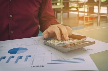 hand working calculate finance about cost with business strategy diagram report, calculator on desk at home office, income and expenses, finance, plan money cost savings, business economy conceptの写真素材