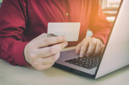 close up hand paying with credit card and typing on laptop computer on desk at home office, payment and shopping online, income and expenses, searching data, social network and check email conceptの写真素材