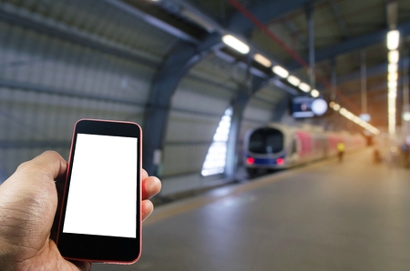 hand using smart phone isolated blank screen with blurred image of subway at railway station, people lifestyle, transportation, technology, internet, network connection, social media conceptの写真素材