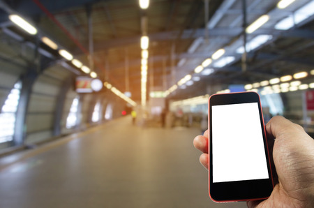 hand using mobile phone with blank screen over blurred view of sky train station, internet, social media technology and network connection conceptの写真素材