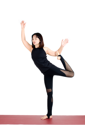 middle aged asian woman doing yoga in Natarajasana or Lord of the Dance Pose yoga pose on the mat isolated on white background, exercise fitness, sport training, healthy lifestyle and people conceptの写真素材