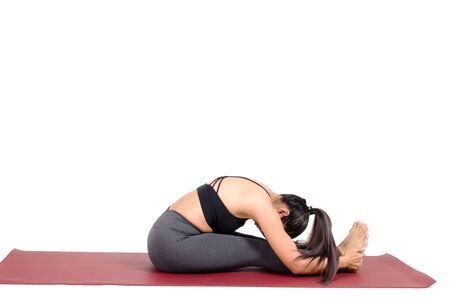 young asian woman doing yoga in Paschimottanasana yoga pose on the mat isolated on white background, exercise fitness, sport training, healthy lifestyle and people conceptの写真素材
