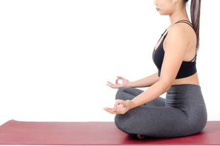 close up side view of young asian woman doing yoga in Padmasana or Lotus yoga pose on the mat isolated on white backgroundの写真素材