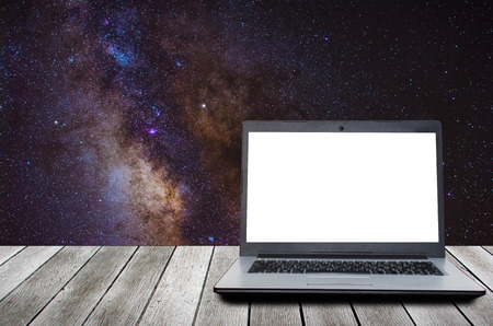 laptop computer with blank screen for presentation on wooden desk, workspace with milky way galaxy, long exposure photograph background, technology, internet and business conceptの写真素材
