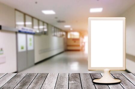 blank menu restaurant plastic holder on wooden desk with blurred image of hospital background background, advertisement, commercial and marketing concept, copy space for text or media contentの写真素材