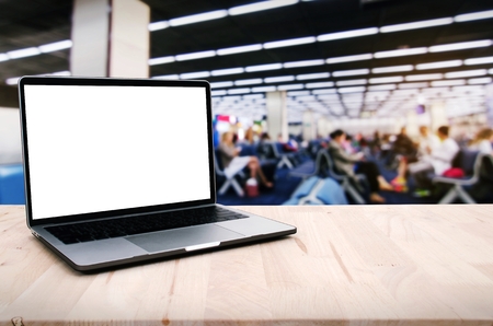 laptop notebook computer with white blank screen on desk with blurred image of people in the airport, advertisement, workspace, internet technology, business and working out of office conceptの写真素材