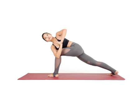young asian woman practicing yoga in Virabhadrasana I or Warrior Twist yoga pose on the mat isolated on white background, exercise fitness, sport training and healthy lifestyle conceptの写真素材