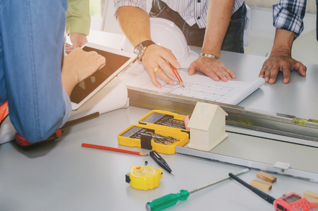 group of engineers, technician and architect planning about building plan with blueprint and construction tools on the conference table at construction site, business, industry, construction conceptの写真素材