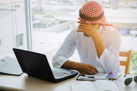 stressed young Arabian business man feel sad worry tired frustrated upset fail after working finance about cost with laptop computer, document on desk at office, emotion, business, investment conceptの写真素材