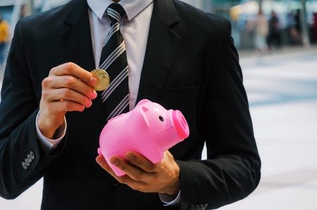 midsection smart business man in black suit holding piggy bank, golden Bitcoin on city background, digital technology, virtual currency, financial, investment, saving money, payment online conceptの写真素材