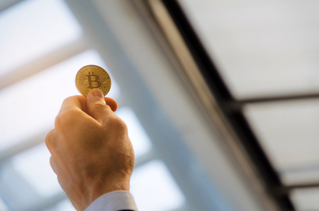 close up business man hand holding golden Bitcoin on city background, digital technology, virtual...