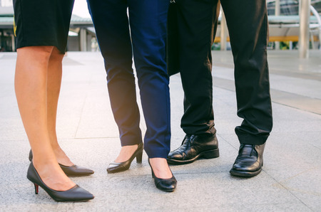 close up legs of group three business people woman and woman team standing at big business district in city together, congratulation, success, meeting, partner, teamwork, community, connection conceptの写真素材