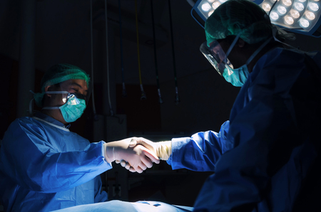 Doctor shaking hands with Assistant after surgeons work for rescue patient in operation room at hospital, emergency case, surgery, medical technology, health care cancer and disease treatment conceptの写真素材