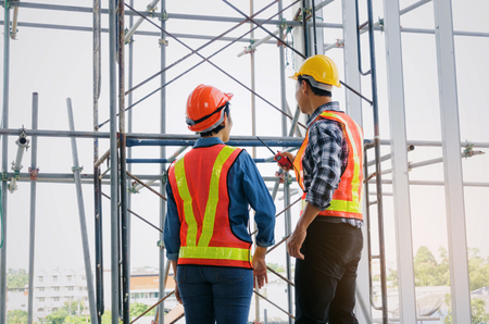 Couple of engineer or technician man and woman with safety helmet holding mobile radio phone...
