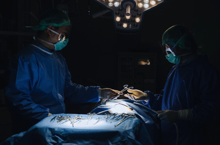 Doctor and Assistant surgeon sending surgical instrument to hand work for rescue patient in operation room at hospital, emergency case, surgery, medical technology, health care cancer, disease conceptの写真素材