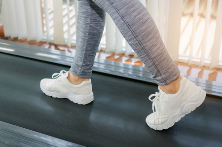 motion of runner woman feet running on machine treadmill at fitness gym center or health club with...