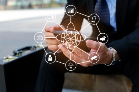 midsection young business man wearing modern black suit using mobile smart phone and briefcase sitting on walkway in city with icon network connection, technology communication and financial conceptの写真素材