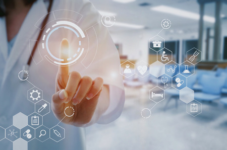female doctor with stethoscope hand pointing touching data digital icon hologram with blurred image of lobby for waiting in hospital background, innovation, medical, future and technology concept.の写真素材