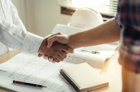 construction worker shaking hands with customer after finishing up business meeting to greeting start up project contract in office center at construction site, business and engineering conceptの写真素材