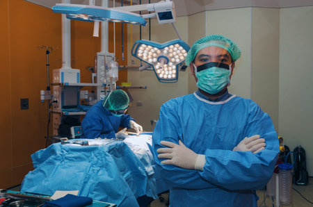 surgeon crossing arms after work for rescue patient in operation room at hospital, health care cancer, emergency case, surgery, medical technology, disease treatment concept, blue color toneの写真素材