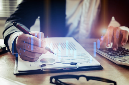 investor or business man analysis on financial reports and using calculator with graphic candle stick graph chart of stock market investment trading for Forex trading, business working conceptの写真素材