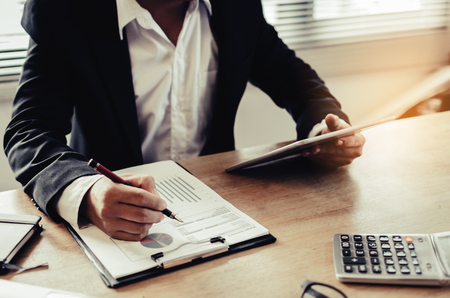 professional investor or business man analysis and calculating on financial reports and using calculator on desk in office, investment, financial adviser, business working and saving money conceptの写真素材