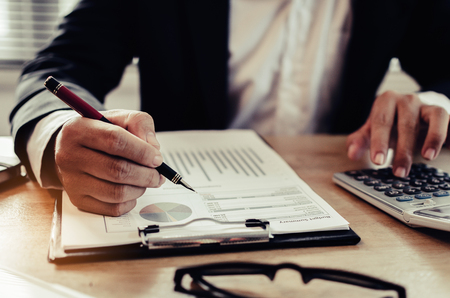professional investor or business man analysis and calculating on financial reports and using calculator on desk in office, investment, financial adviser, business working and saving money conceptの写真素材