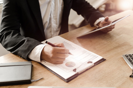 professional investor or business man analysis and calculating on financial reports and using mobile tablet on desk in office, investment, financial adviser, business working and savings money conceptの写真素材