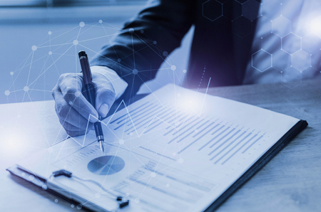 professional investor or business man analysis and calculating on financial reports on desk in office with graphic graph chart of stock market investment trading, financial and technology conceptの写真素材