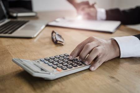 professional investor or business man analysis and calculating on financial reports and using calculator on desk in office, investment, financial adviser, business working and saving money conceptの写真素材