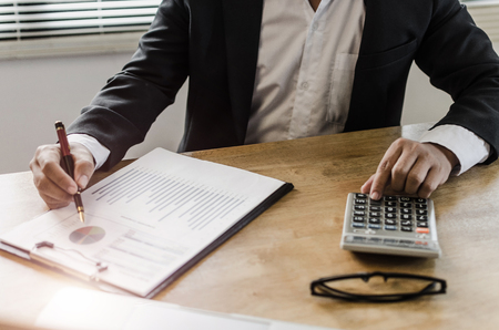professional investor or business man analysis and calculating on financial reports and using calculator on desk in office, investment, financial adviser, business working and saving money conceptの写真素材