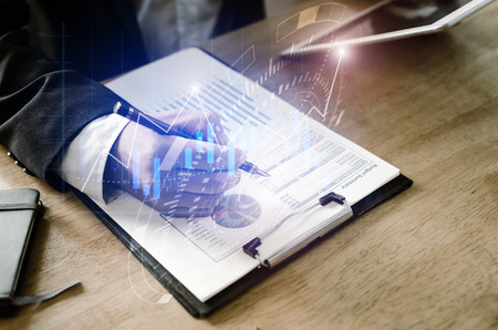 investor or accountant analysis on financial reports with mobile tablet with graphic candle stick graph chart of stock market investment trading for Forex trading, technology, business working conceptの写真素材