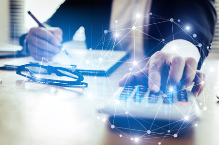 professional investor or business man analysis and calculating on financial reports on desk in office with graphic graph chart of stock market investment trading, financial and technology conceptの写真素材