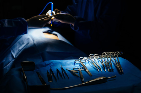 surgical instrument lying on table while group of surgeon performing work in operation room at hospital, emergency case, surgery, medical technology, health care cancer and disease treatment conceptの写真素材