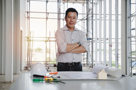 smart engineer, architect or technician crossing arms with construction tools on the conference table in construction site building to greeting start up project, contractor and engineering conceptの写真素材
