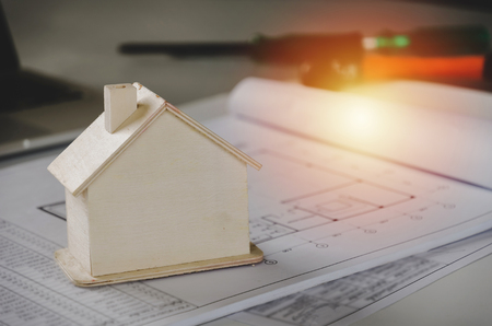 close up image of wooden house model with blueprint and tools on conference table for plan start up project in construction site, real estate, architecture, construction and contractor conceptの写真素材