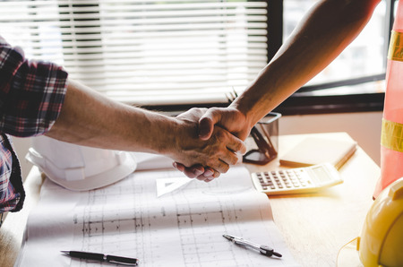 view of construction worker team contractor hand shake after finishing up business meeting to...