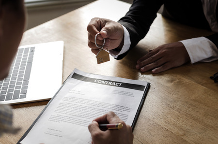 real estate broker manager giving house key to customer after signing contract for buying house in estate agent office, investment, home loan contract, selling house, realtor and real estate conceptの写真素材