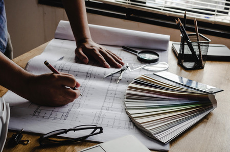 professional architect, engineer or interior drawing on blueprint with laptop and color palette on workplace desk in office center at construction site, contractor, construction, engineering conceptの写真素材
