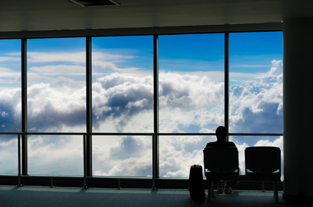 silhouette of business tourist people with luggage looking at blue sky with clouds and and waiting at the plane boarding gates before departure in airport, travel, lifestyle and transportation conceptの写真素材
