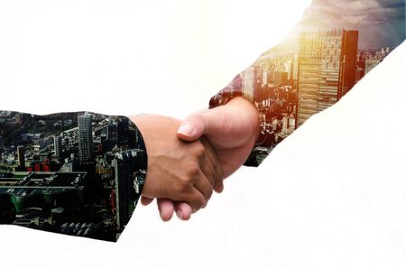 Partnership. double exposure image of investor business man handshake with partner for successful meeting deal with during sunrise and cityscape background, investment, partnership, teamwork conceptの写真素材